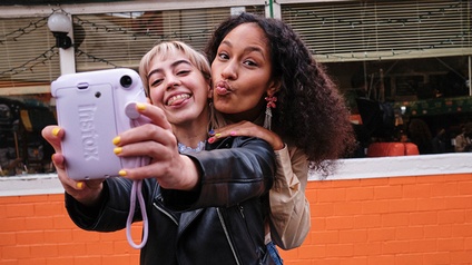 Zwei Mädchen posen mit Sofortbildkamera