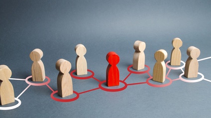 Konzept Teamwork und Zusammenarbeit in einem Netzwerk bestehend aus Holzfiguren und einer rot gefärbten Figur