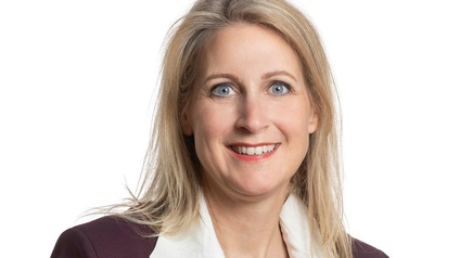 Person mit blondem Haar und Bluse in einem Portrait 