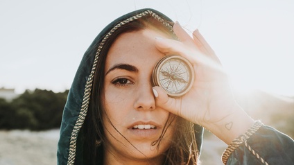 NUR FÜR Werbekampagne G’SPÜR_Frau steht in einem Feld und hält einen Kompass in der Hand