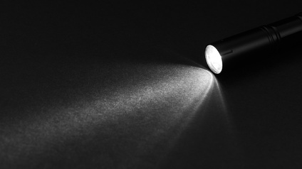 Taschenlampe wirft Licht auf dunklen Boden