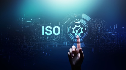 Vektor-Illustration eines bläulichen Hintergrunds, auf dem ISO steht. Um diese Buchstaben sind mehrere Zahnräder gelegt. Direkt rechts daneben ist ein Kreis mit einem Haken, auf den der rechte Zeigefinger einer Person deutet