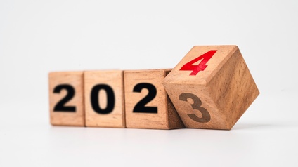 Holzwürfel mit schwarzen Zahlen, die 2023 anzeigen, der letzte Würfel bewegt sich und hält eine rote 4 für den Übergang zum Jahr 2024 parat