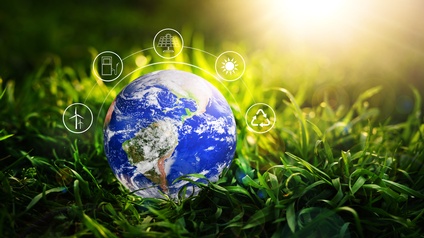 Weltkugel ist auf einem grünen Gras platziert, darüber zeigt sich eine grafische Visualisierung zum Thema Umwelt, Energie und Nachhaltigkeit, Sonnenstrahlen ragen von oben in das Bild hinein
