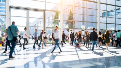 Personen gehen durch eine helle Eingangshalle aus Glas