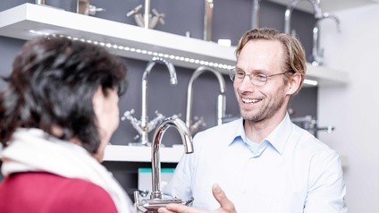 Ein Installateur mit einem Wasserhahn in der Hand bei der Kundeberatung