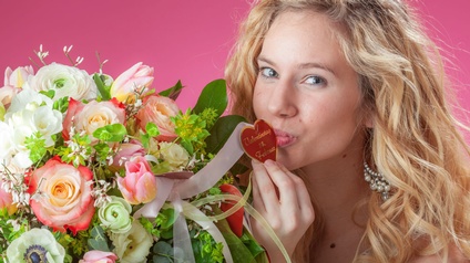 Person macht einen Kussmund neben einem großen Blumenstrauss