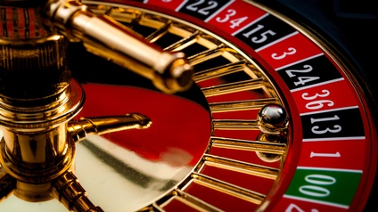 Nahaufnahme eines goldenen Roulette-Rades mit einer Kugel, die im schwarzen Feld 13 liegt