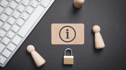 Karte mit Informationssymbol, Holzfiguren, Schloss und Tastatur auf einem dunklen Untergrund, Topshot