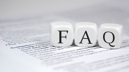 Drei weiße Würfel liegen nebeneinander auf einem bedruckten Papier. Auf dem linken Würfel ist ein f, dann folgt ein a und dann ein q