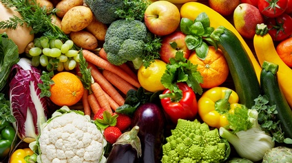 Nahaufnahme vieler verschiedener Gemüse- und Obstsorten, die auf einem Haufen liegen, zum Beispiel Kartoffeln, Zucchini, Orangen, Tomaten, Paprika, Melanzani, Karfiol, Weintrauben, Karotten, Basilikum, Fenchel, Artischocken, Radicchio, Erdbeeren.