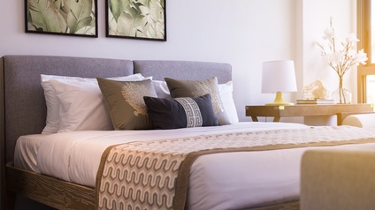 Blick auf einen Raum mit modernem Bett und erdigen Farbtönen