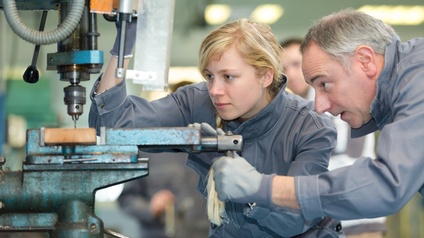 Lehrlingsmädchen und Ausbildner an einer Maschine