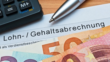 Detailansicht Spitze eines Kugelschreibers, Ausschnitt eines Taschenrechners, Eurogeldscheine und Dokument mit Schriftzug  Lohn-/Gehaltsabrechnung
