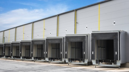 Halle mit nummerierten Laderampen für LKWs unter blauem Himmel