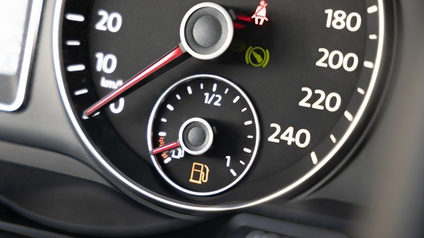 Detailansicht eines Cockpits in einem Auto mit rot leuchtenden Warnanzeigen für den Tankstand sowie für das Anschnallen