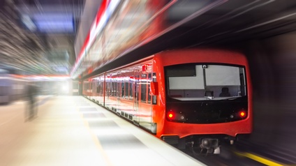 Eine rote U-Bahn mit mehreren Waggons fährt vom Bahnsteig ab