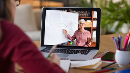 Laptop-Bildschirm mit Person die auf Tafel zeigt, vor Laptop Person sitzend, die Notizen macht