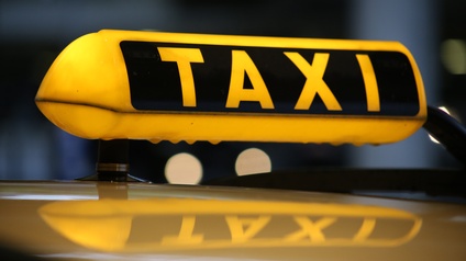 Ein gelb leuchtendes Taxischild auf einem Fahrzeug bei Nacht