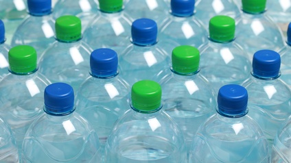 Mehrere Plastikflaschen mit Wasser und blauen und grünen Verschlüssen in Vogelperspektive