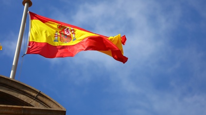 Die Flagge Spaniens im Wind wehend unter blauem Himmel.