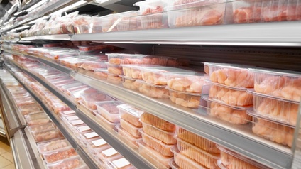 Kühlregal mit mehreren Ebenen gefüllt mit in Plastikschalen verpacktem Geflügelfleisch