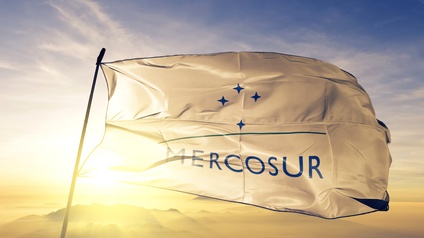 Weiße Fahne mit Mercosur Schrift und Sternen weht bei Abenddämmerung