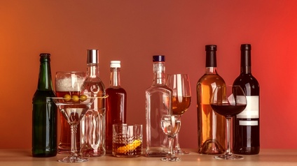 Tisch mit mehreren Flaschen Spirituosen und Gläsern vor einer roten Wand