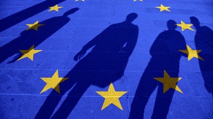 Blauer Boden mit im Kreis verlaufenden gelben Sterne, die Flagge der Europäischen Union symbolisierend, Schattenumrisse von vier Personen erkennbar