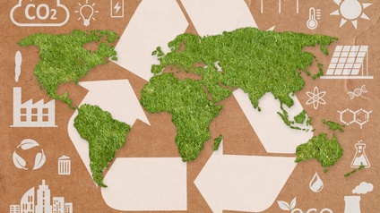 Eine grafische Darstellung einer grünen Weltkarte auf einem weißem Recycling-Symbol mit Ökologie-Icons auf einem Kartonhintergrund.
