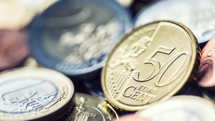 50 Cent Euro Münze im Blickfeld, andere Münzen liegen verschwommen im Hintergrund