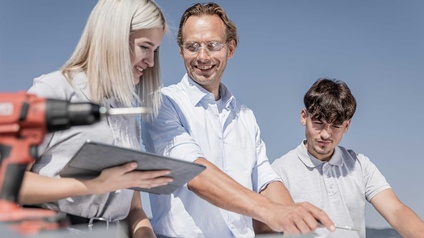 Drei Personen betrachten einen Gebäudeinstallationsplan