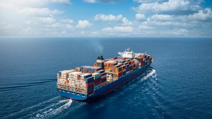 Ein Frachtschiff mit vielen Containerstapeln auf dem offenen Meer