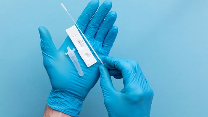 Negativer Covid-Antigen-Test liegt mit Teststäbchen und Flüssigkeitsröhrchen auf Hand in blauem Gummihandschuh