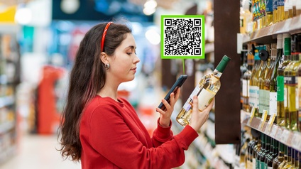 Person steht vor Weinregal in Supermarkt und hält in einer Hand Weißweinflasche, in anderer Hand Smartphone von dem grün gerahmtes Kästchen mir QR-Code emporsteigt
