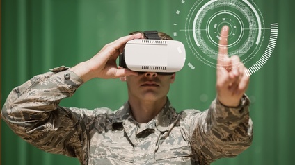 Eine Person in einer Militäruniform trägt eine VR-Brille auf dem Kopf und berührt mit dem linken Zeigefinger eine virtuelle Zielscheibe