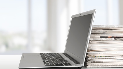 Laptop an Zeitungsstapel lehnend