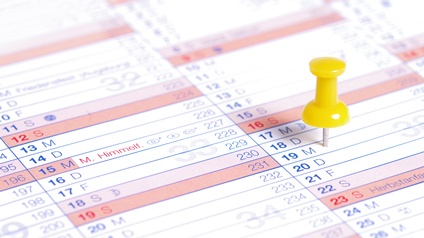 Detailansicht gelber Pinnadel in Kalender steckend