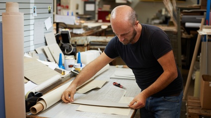 Eine Person misst die Seiten eines Papiers für die Herstellung eines Buches in einer Buchbinderei ab.