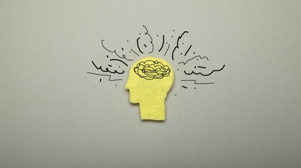 Grafische Darstellung gelber Kopf in Seitenansicht mit Gehirn und Linien, die Kopf umgeben
