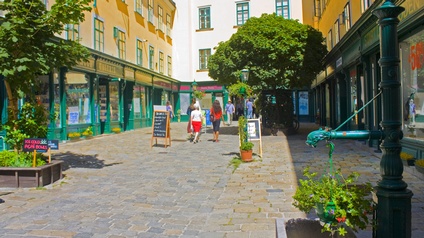 Eine heller, begrünter Fußgängerdurchgang durch den Raimundhof in Wien im Sommer.