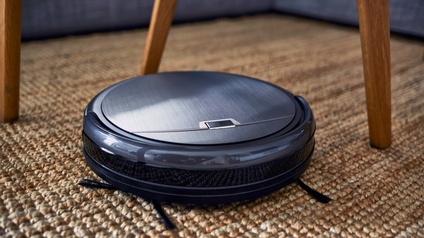 Nahaufnahme eines Staubsaugerroboters auf einem Teppich.