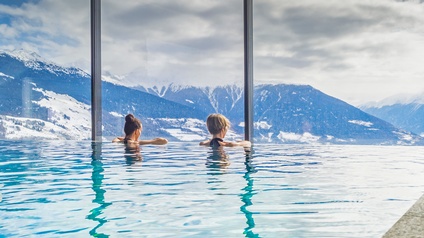 Personen in einem Indoor-Pool genießen Ausblick auf ein Bergpanorama