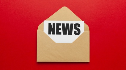 Geöffneter hellbrauner Briefumschlag mit weißem Blatt und Aufschrift News vor einem roten Hintergrund