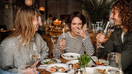 Vier Personen sitzen in einem Lokal um einen Tisch. 