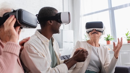 Personen verschiedener Generationen sitzen freudig gemeinsam auf einem Sofa und tragen eine Virtual Reality Brille