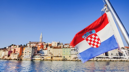 Die kroatische Flagge weht im Wind, im Hintergrund eine Stadtansicht.
