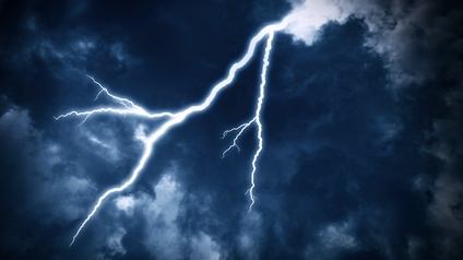 Ein bewölkter Himmel mit dunklen Gewitterwolken, durch die ein Blitz fährt