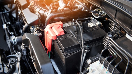 Detailansicht auf den Motorraum eines Autos mit Fokus auf die Batterie.