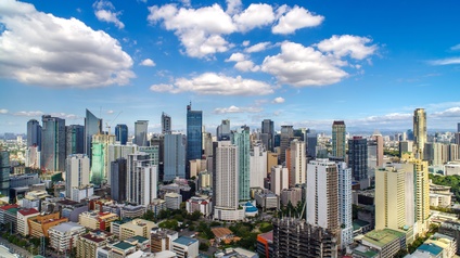 Panoramablick auf Manila mit etlichen Wolkenkratzern unter blauem Himmel und weißen Wolken. 